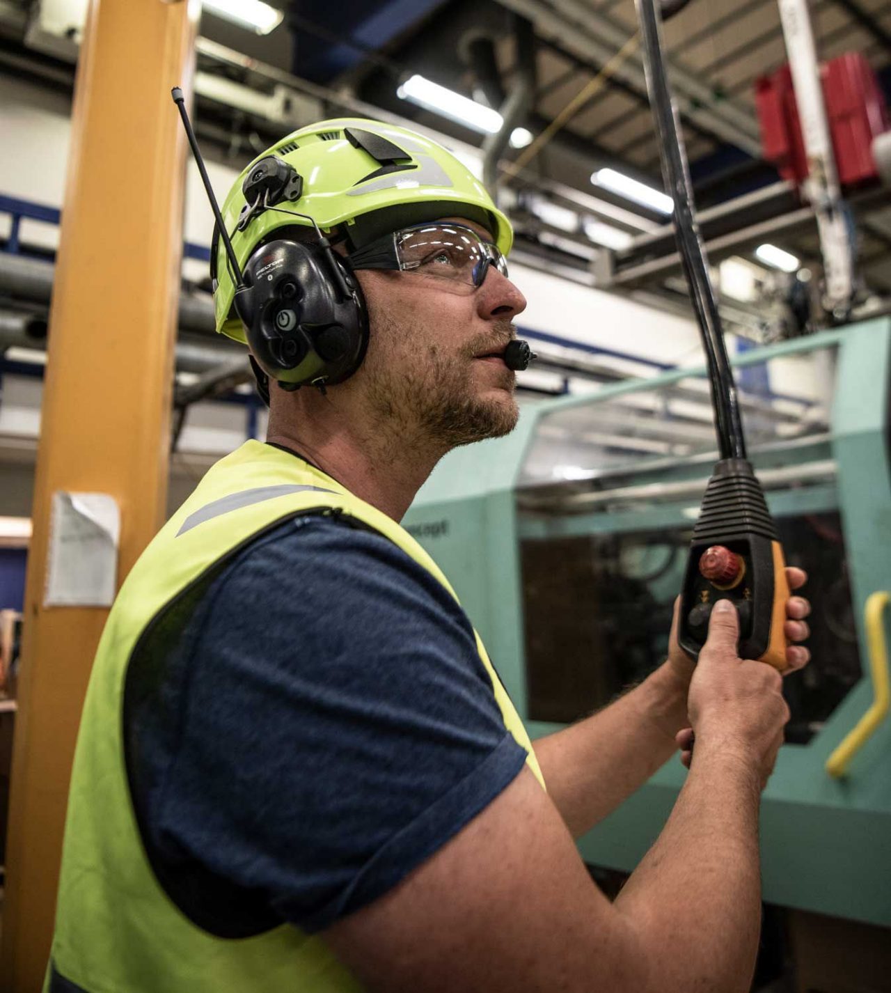 man inside with machinery wearing yellow helmet with headphones with Bluetooth communication features
