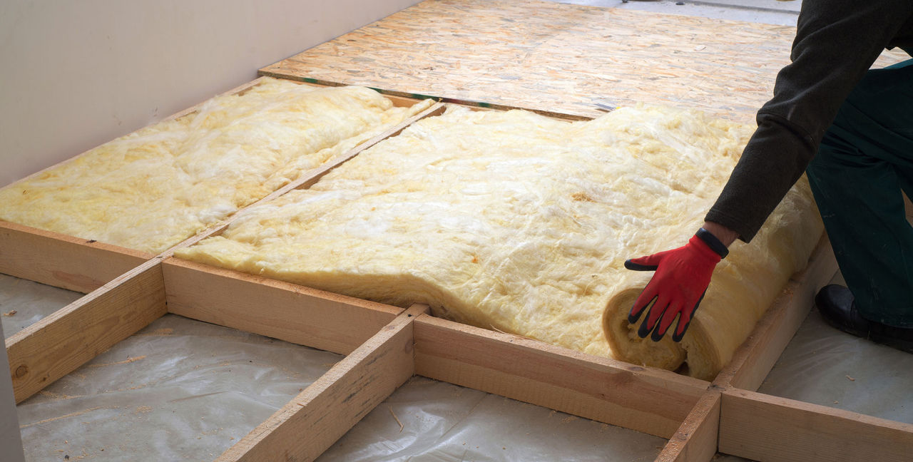 Work composed of mineral wool insulation in the floor, floor heating insulation , warm house, eco-friendly insulation, a builder at work